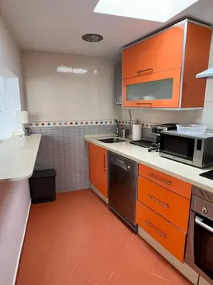a small kitchen with orange cabinets and a microwave at La Candela by Gades Gestión in Cádiz