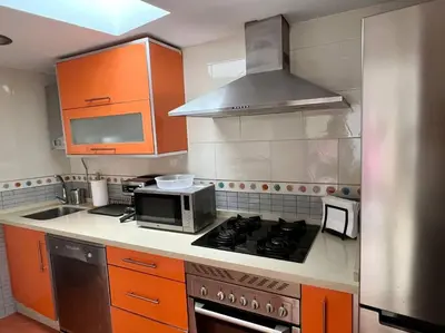 a kitchen with orange cabinets and a microwave at La Candela by Gades Gestión in Cádiz