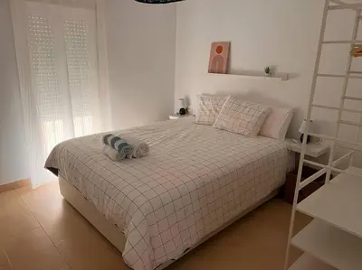 a bedroom with a bed with a blanket and a shelf at La Candela by Gades Gestión in Cádiz