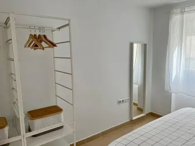 a white bedroom with a bed and a mirror at La Candela by Gades Gestión in Cádiz