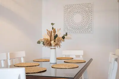 a dining room table with four chairs and a vase with flowers at SibsSanlucar Azahar Centrico Vistas Terraza Coqueto in Sanlúcar de Barrameda