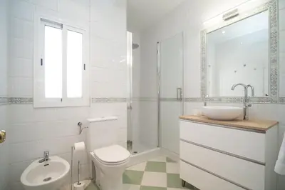 a white bathroom with a toilet and a sink at SibsSanlucar Azahar Centrico Vistas Terraza Coqueto in Sanlúcar de Barrameda