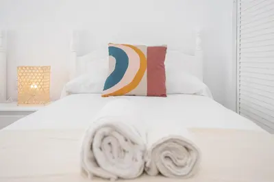 a white bedroom with a white bed with pillows at SibsSanlucar Azahar Centrico Vistas Terraza Coqueto in Sanlúcar de Barrameda