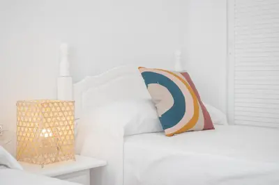 a white bedroom with a bed with a pillow on it at SibsSanlucar Azahar Centrico Vistas Terraza Coqueto in Sanlúcar de Barrameda