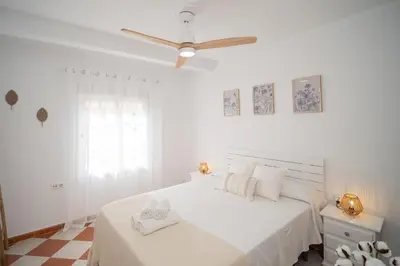 a white bedroom with a bed and a ceiling fan at SibsSanlucar Azahar Centrico Vistas Terraza Coqueto in Sanlúcar de Barrameda