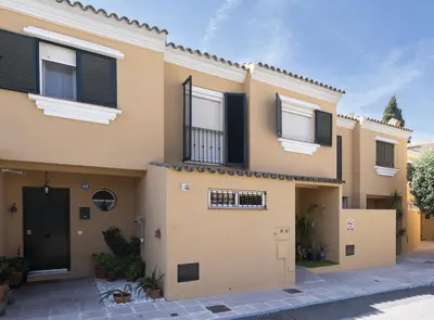 a house with black shutters on it at Chalet Pareado & Piscina in El Puerto de Santa María
