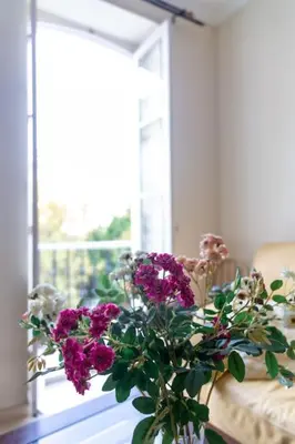 a vase with purple flowers sitting in front of a window at Alameda by Gades Gestión in Cádiz
