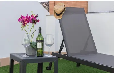 a table with a bottle of wine and two glasses at ÁTICO Edificio RIANAL in Jerez de la Frontera