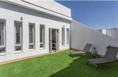 a patio with two chairs and green grass at ÁTICO Edificio RIANAL in Jerez de la Frontera