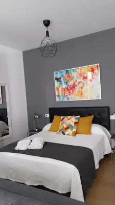 a bedroom with two beds and a painting on the wall at ÁTICO Edificio RIANAL in Jerez de la Frontera