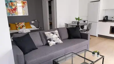 a living room with a gray couch and a table at ÁTICO Edificio RIANAL in Jerez de la Frontera
