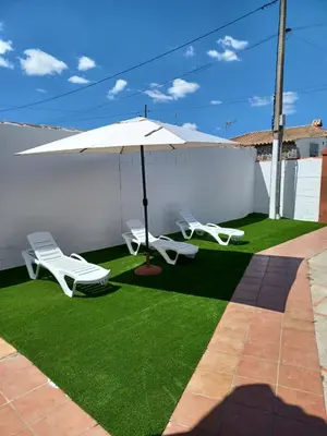 a patio with two lawn chairs and an umbrella at Villa TRANQUILA in Chiclana de la Frontera