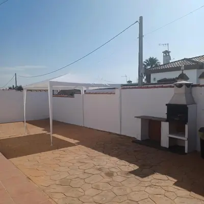 a patio with a table and a grill on a white wall at Villa TRANQUILA in Chiclana de la Frontera
