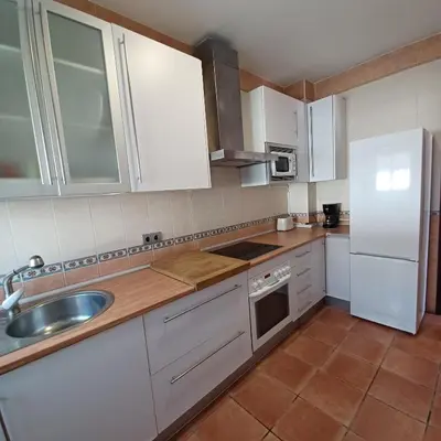 a kitchen with white cabinets and a sink and a refrigerator at Villa TRANQUILA in Chiclana de la Frontera