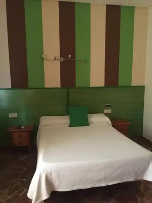 a bedroom with a white bed with green and brown stripes at Hotel Arcos-Coruña in Arcos de la Frontera