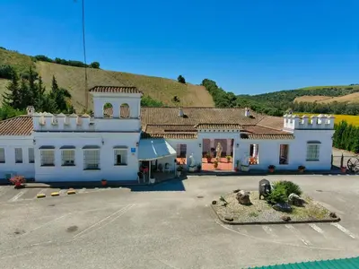 a large white building with a hill in the background at Hotel Arcos-Coruña in Arcos de la Frontera