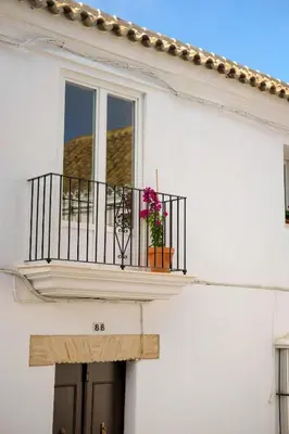 a white building with a balcony with flowers on it at El Sur Medina-Sidonia in Medina Sidonia