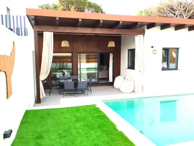 a house with a swimming pool and a patio at villa woody playa in Chiclana de la Frontera