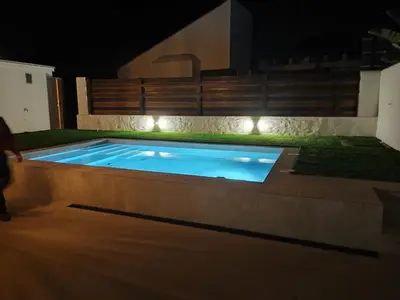 a swimming pool at night with lights around it at villa woody playa in Chiclana de la Frontera