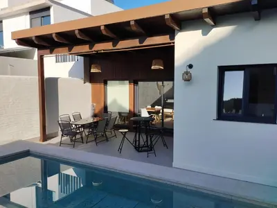 a patio with a table and chairs next to a pool at villa woody playa in Chiclana de la Frontera
