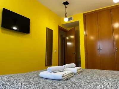 a bedroom with yellow walls and a bed with towels at Penthouse San Felix Grupo AC Gestion in Cádiz