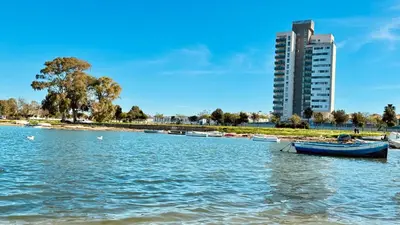 a group of boats on the water with a tall building at Bahía Azul Suites, Piscina & Pádel in San Fernando