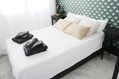 a bedroom with a white bed with a black purse on it at Coqueto encantador en el centro in El Puerto de Santa María