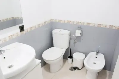 a white bathroom with a toilet and a sink at Coqueto encantador en el centro in El Puerto de Santa María