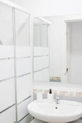 a white bathroom with a sink and a mirror at Coqueto encantador en el centro in El Puerto de Santa María