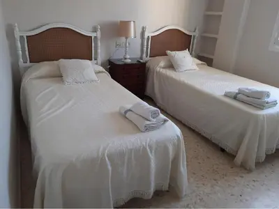 two beds with towels on them in a bedroom at El Parque 4 dormitorios wifi playa centro in Sanlúcar de Barrameda