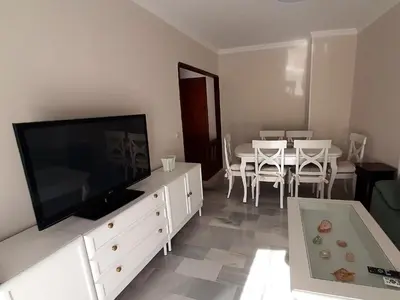a living room with a television and a table with chairs at El Parque 4 dormitorios wifi playa centro in Sanlúcar de Barrameda