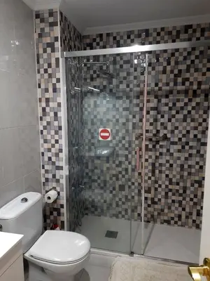 a bathroom with a toilet and a glass shower at El Parque 4 dormitorios wifi playa centro in Sanlúcar de Barrameda