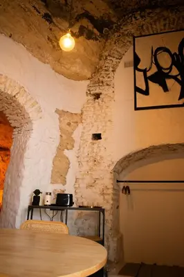 a dining room with a table in a stone wall at Laan Arcos, casa cueva in Arcos de la Frontera