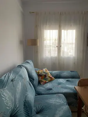a blue couch in a living room with a window at Bonita casa cerca de la playa in Chipiona