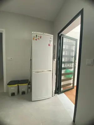 a white refrigerator in a room with two trash cans at Bonita casa cerca de la playa in Chipiona