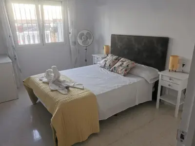 a white bedroom with a bed and a table at Bonita casa cerca de la playa in Chipiona