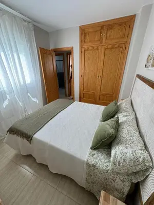 a bedroom with a large bed and a wooden cabinet at Apartamentos Modern Homes in Chiclana de la Frontera