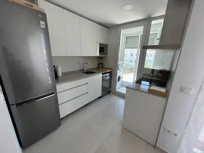 a kitchen with white cabinets and a stainless steel refrigerator at Apartamento en Costa Ballena in Chipiona