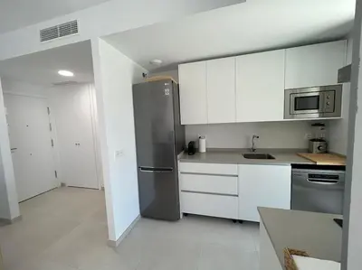 a kitchen with white cabinets and a stainless steel refrigerator at Apartamento en Costa Ballena in Chipiona