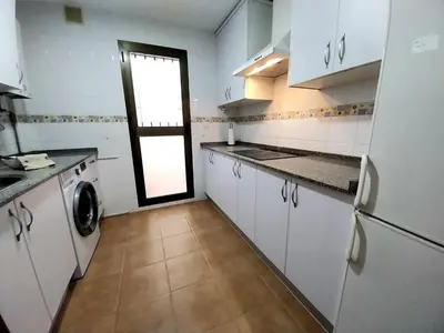 a kitchen with white cabinets and a washer and dryer at Tempul Garden Suite in Jerez de la Frontera