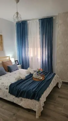 a bedroom with a large bed with blue curtains at Apartamento Viñedos de Librado in Jerez de la Frontera