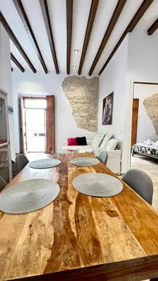 a large wooden table with four chairs and a living room at Apartamento bodegas de Cazón Barrio San Miguel in Jerez de la Frontera