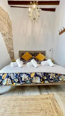 a bed in a room with a chandelier at Apartamento bodegas de Cazón Barrio San Miguel in Jerez de la Frontera