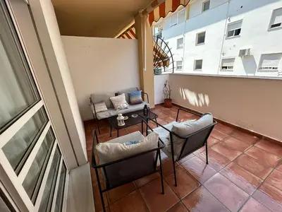 a balcony with chairs and a table and a couch at La Marina, apartamento in Sanlúcar de Barrameda