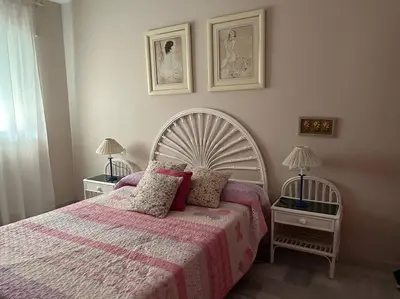 a bedroom with a large bed with a pink blanket at La Marina, apartamento in Sanlúcar de Barrameda