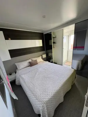 a bedroom with a large white bed and a mirror at Mobil Home La Barrosa in Chiclana de la Frontera