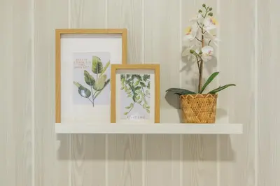 a shelf with three pictures and a vase of flowers at Geminis in Rota