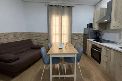 a kitchen and a living room with a table and a couch at Apartamento Caleta Beach in Cádiz