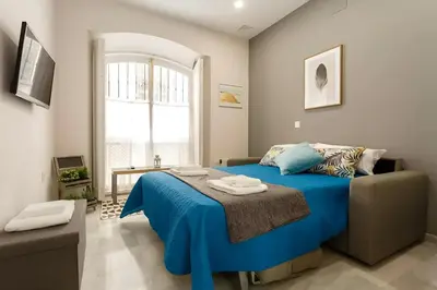 a bedroom with a blue bed and a window at Loft El Capricho Grupo Ac Gestion in Cádiz