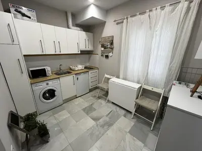 a kitchen with white cabinets and a washer and dryer at Loft El Capricho Grupo Ac Gestion in Cádiz
